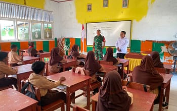 Guru dan tentara berbicara di depan kelas saat siswa duduk mendengarkan